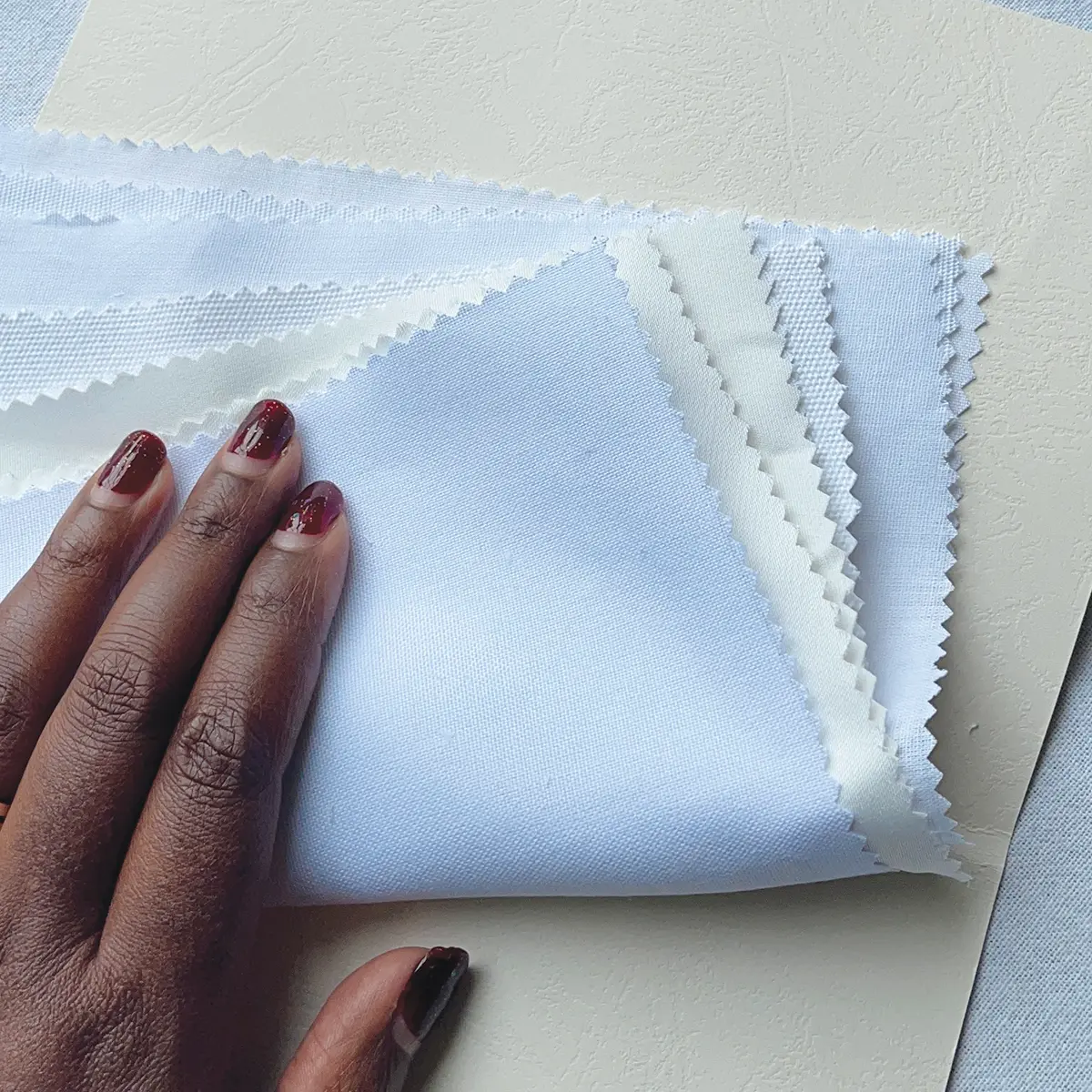 UndaMeta Fabric Swatch Catalogue showing the actual fabric types inside catalogue, a hand holds them down